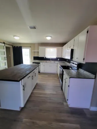 a large kitchen with stainless steel appliances granite countertop a stove a sink dishwasher and a microwave oven with wooden floor