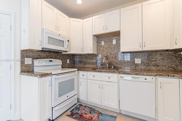 a kitchen with granite countertop white cabinets and white appliances