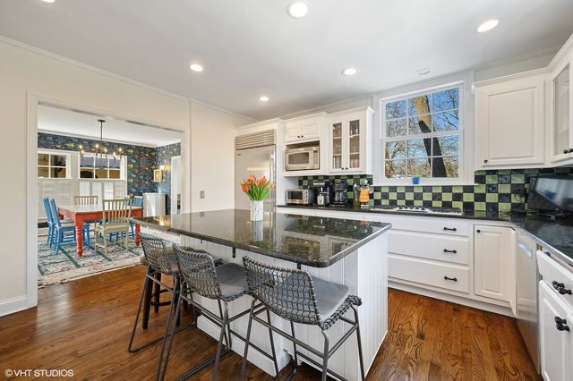 a kitchen with stainless steel appliances granite countertop a stove a sink dishwasher and a dining table with wooden cabinet