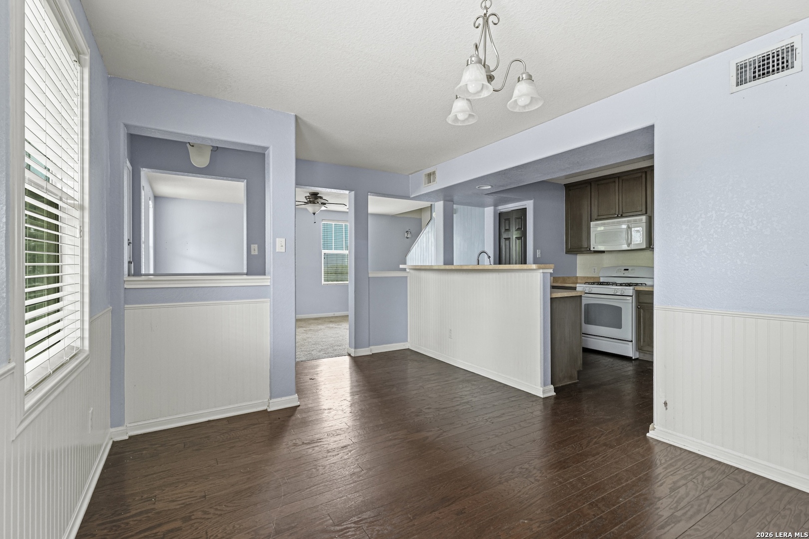 202 Trestle Tree San Marcos, TX 78666 - Photo 3 of 22 an empty room with wooden floor and a kitchen