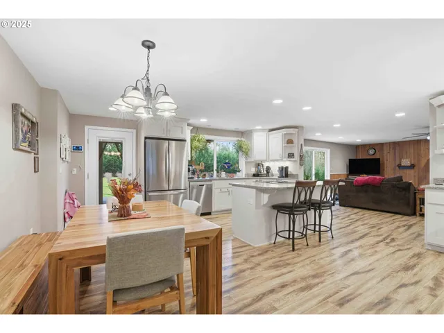 a kitchen with stainless steel appliances a sink a stove a refrigerator with white cabinets and wooden floor