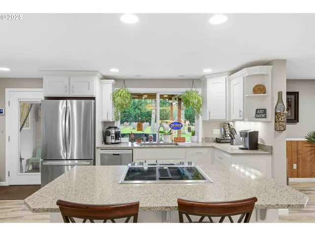 a room with stainless steel appliances kitchen island granite countertop furniture and a chandelier