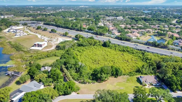 an aerial view of a residential houses with outdoor space and trees