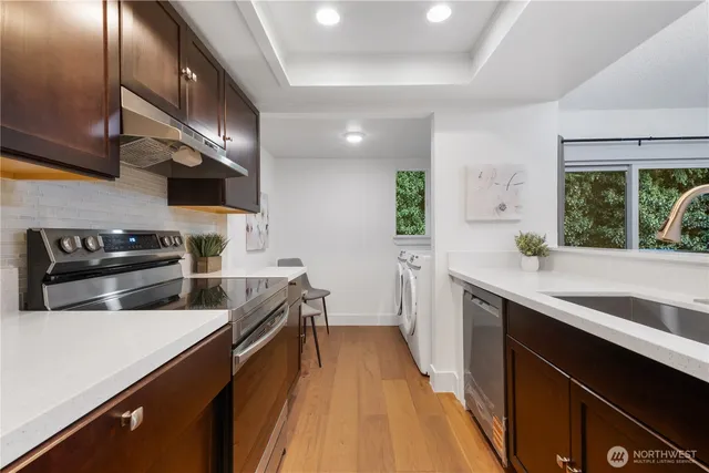 a kitchen with stainless steel appliances a sink dishwasher a stove top oven a refrigerator with wooden floor