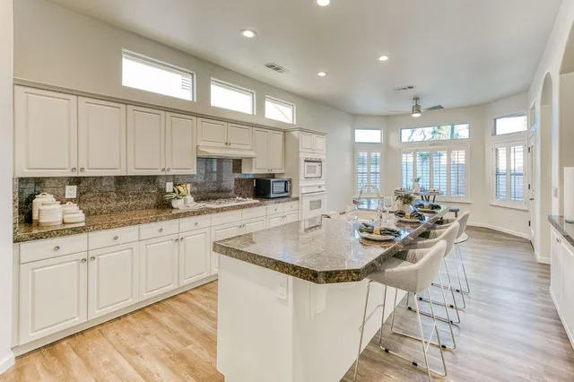 a large kitchen with kitchen island a large counter top stainless steel appliances and cabinets