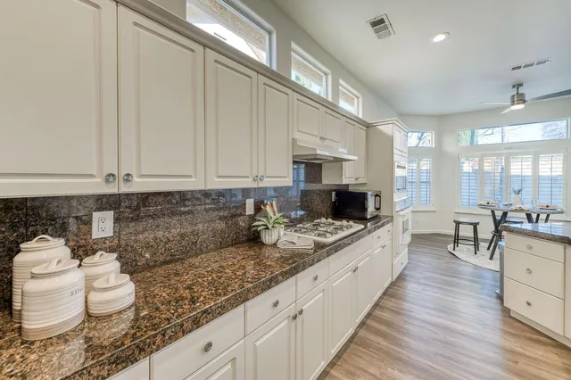 a kitchen with granite countertop kitchen island white cabinets and stainless steel appliances