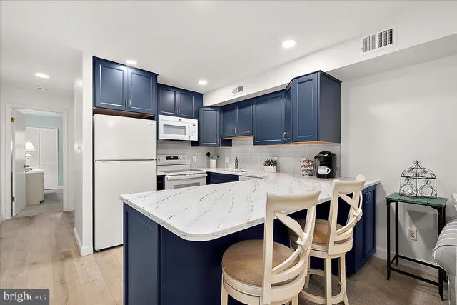 a kitchen with a dining table chairs refrigerator and microwave