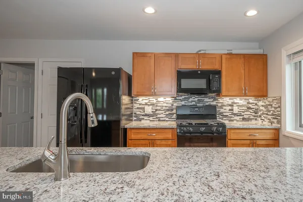 a kitchen with stainless steel appliances granite countertop a stove a sink and a microwave
