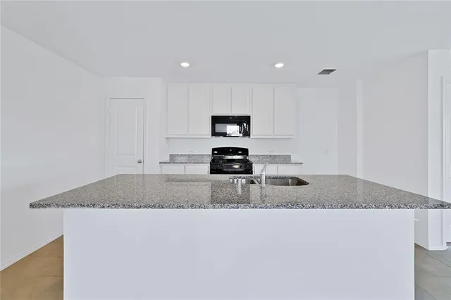 a kitchen with granite countertop a stove and a white cabinets