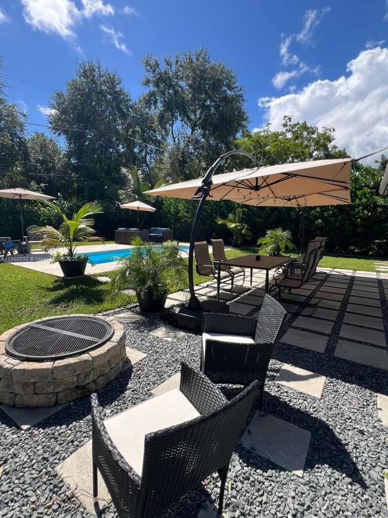 1430 Northeast 149th Street Miami, FL 33161 - Photo 11 of 51 a view of a patio with table and chairs potted plants and a palm tree