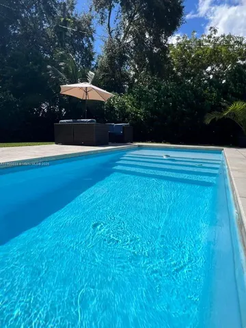 a view of swimming pool with lawn chairs under an umbrella