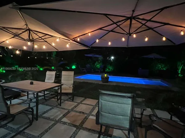 a view of a swimming pool with lawn chairs under an umbrella
