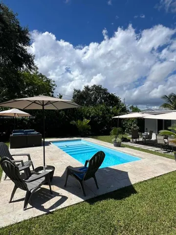 a view of pool with lawn chairs and a yard
