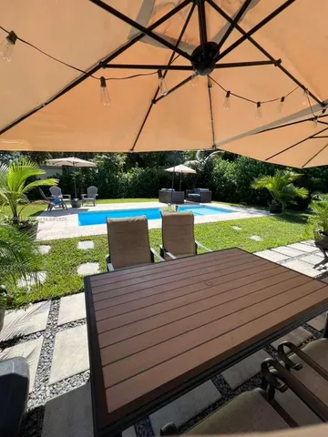 a view of a patio with table and chairs potted plants and a palm tree