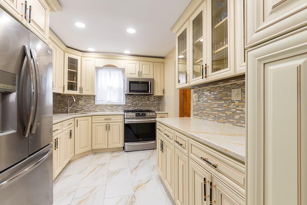 Kitchen with cream cabinetry, stainless steel appliances, and a sink