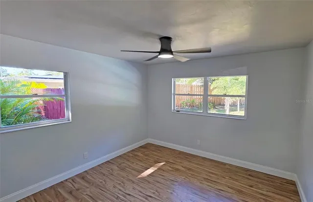 a view of an empty room with window and wooden floor