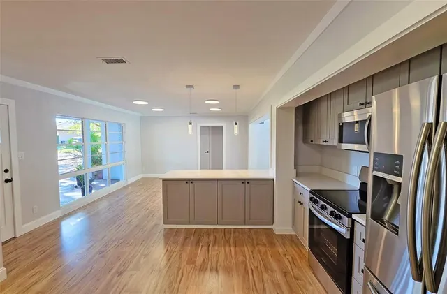 a large kitchen with a wooden floor and stainless steel appliances