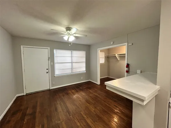 an empty room with wooden floor chandelier fan and windows