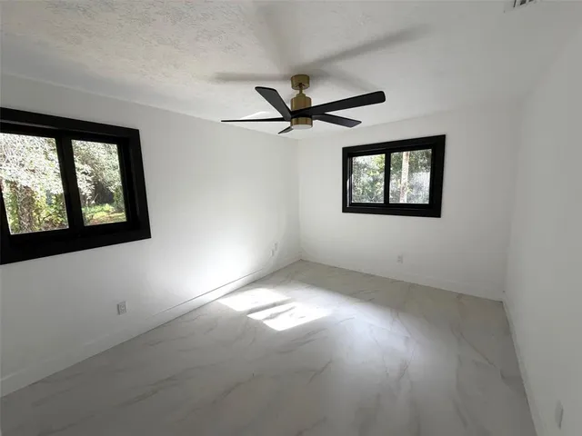 an empty room with windows and fan