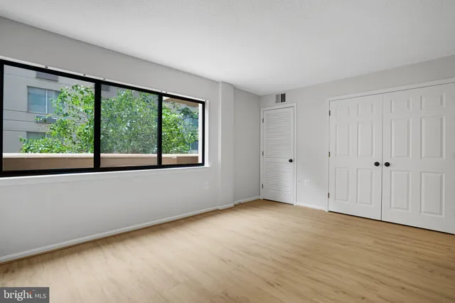 a view of an empty room with wooden floor and a window