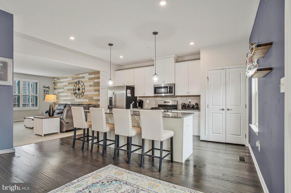 8218 Kippis Road Millersville, MD 21108 - Photo 12 of 40 a kitchen with stainless steel appliances kitchen island granite countertop a dining table chairs and white cabinets