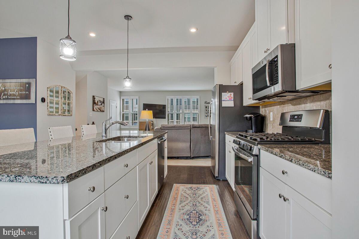 8218 Kippis Road Millersville, MD 21108 - Photo 10 of 40 a kitchen with stainless steel appliances granite countertop a stove top oven a sink dishwasher a refrigerator and a oven with wooden floor