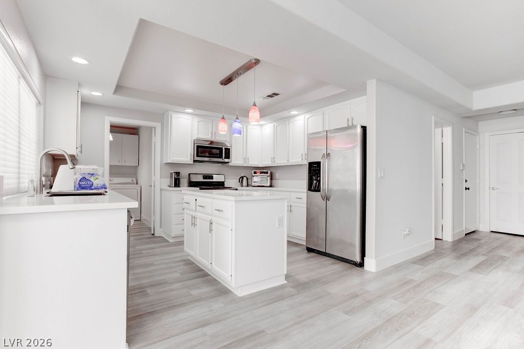 1 Rising Sun Court Henderson, NV 89074 - Photo 11 of 47 White cabinetry, sleek appliances, and a central island define this open-concept kitchen space.