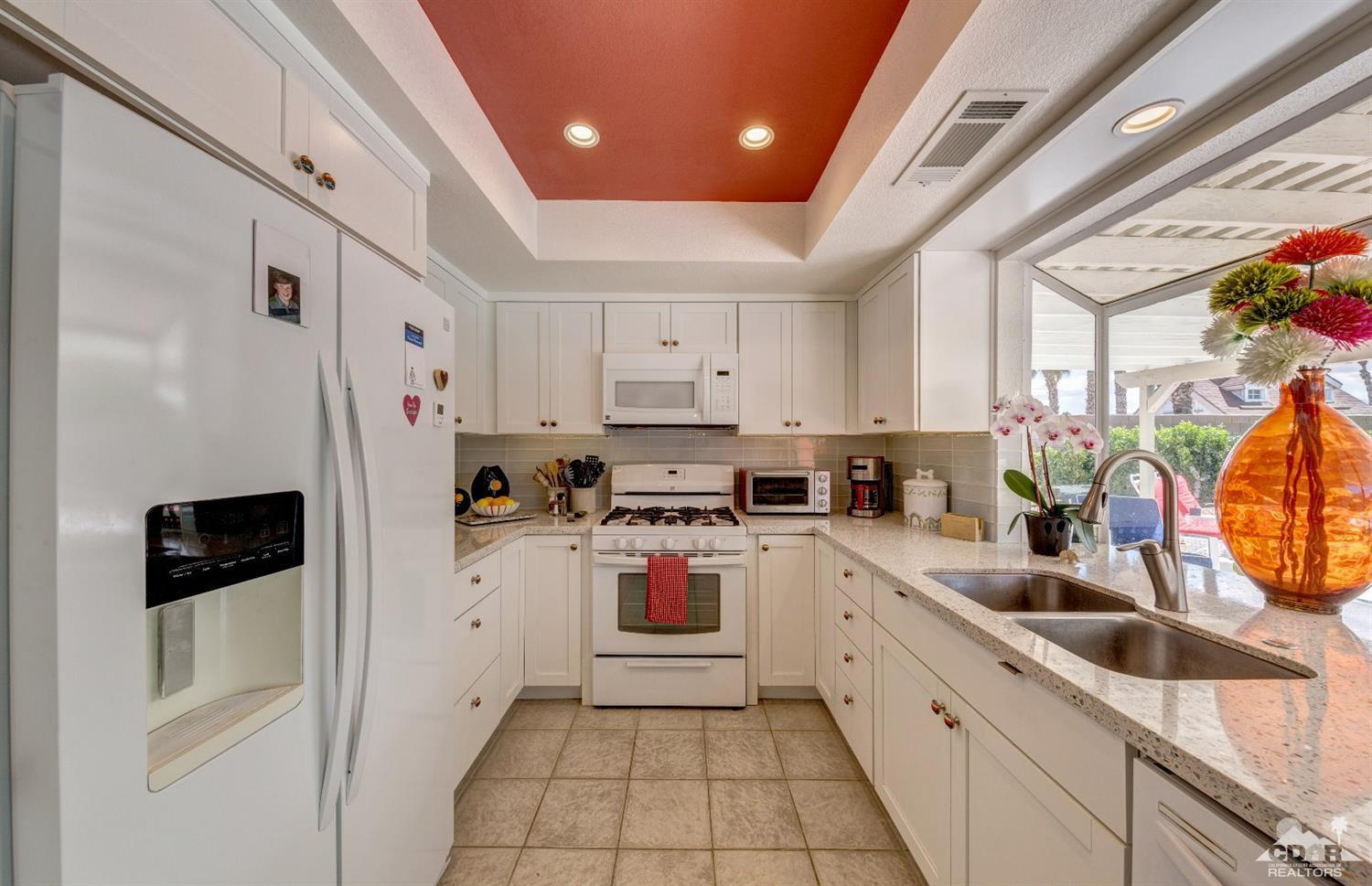 68365 Encinitas Road Cathedral City, CA 92234 - Photo 5 of 25 a kitchen with white cabinets and white appliances