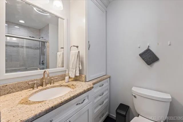 a bathroom with a granite countertop sink a mirror and a toilet