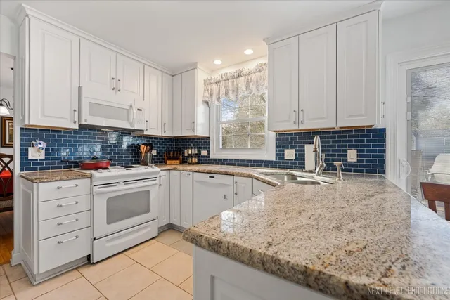 a kitchen with granite countertop white cabinets and white appliances