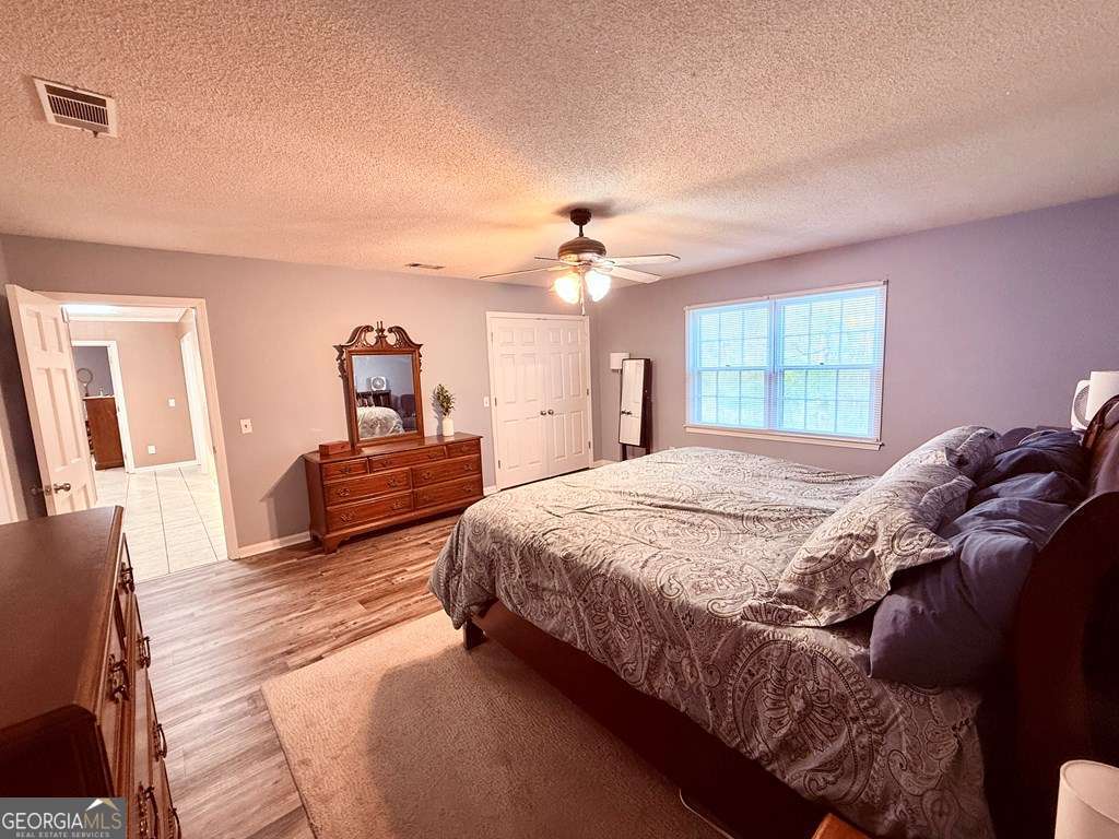 1881 Bell Telephone Road Hazlehurst, GA 31539 - Photo 45 of 71 a spacious bedroom with a bed a chandelier and dresser