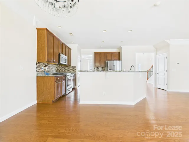 a view of a kitchen with kitchen island a sink a stove and wooden floor