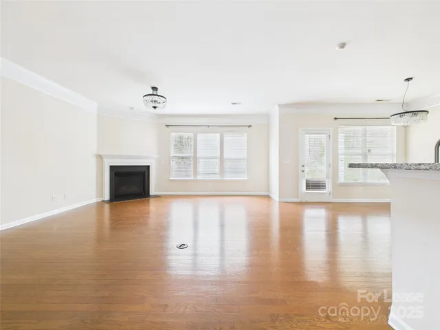 a view of an empty room with window and wooden floor