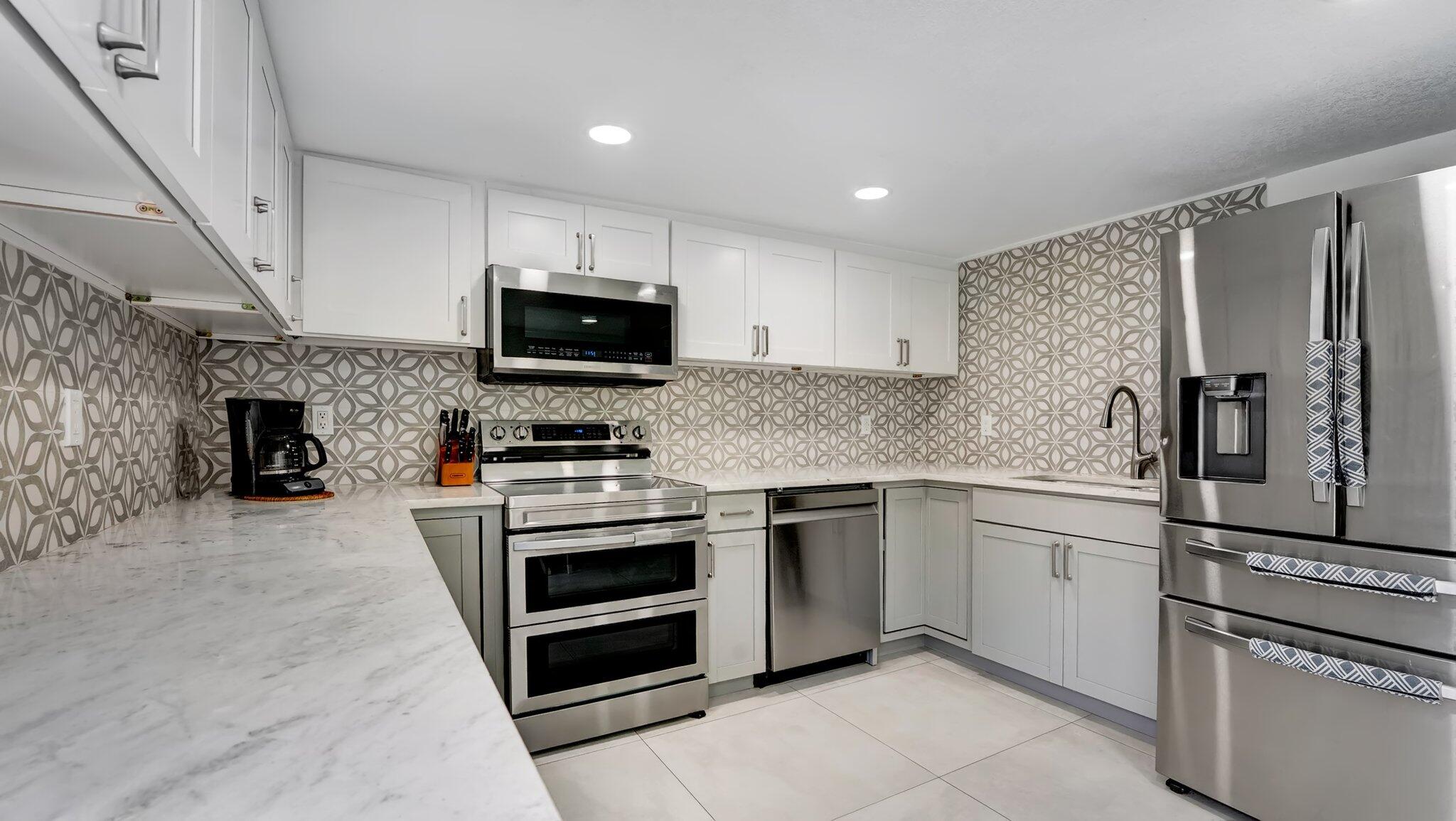 9709 Southwest 1st Place Boca Raton, FL 33428 - Photo 16 of 32 a kitchen with granite countertop a refrigerator and a stove top oven