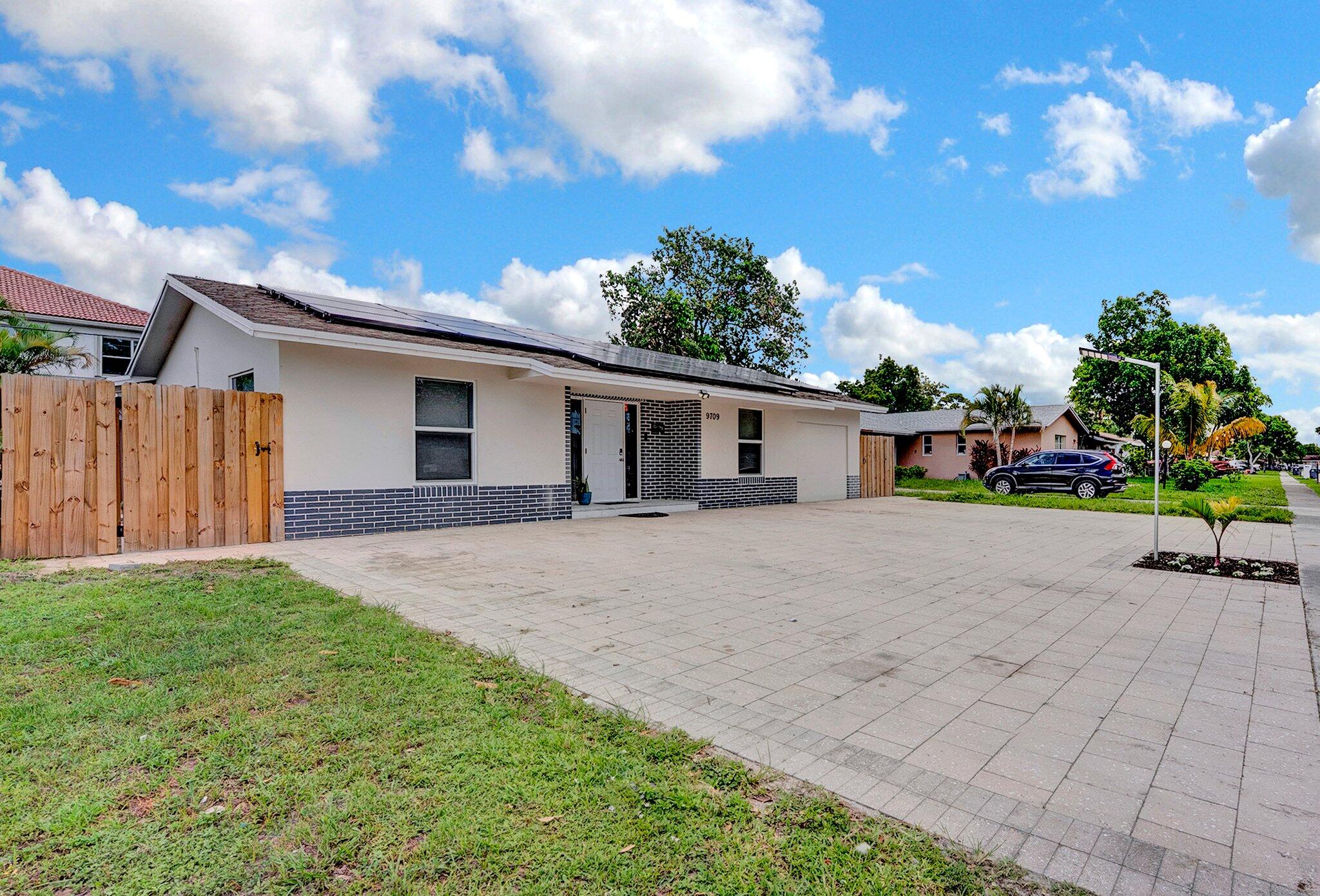 9709 Southwest 1st Place Boca Raton, FL 33428 - Photo 2 of 32 a front view of a house with a garden and yard