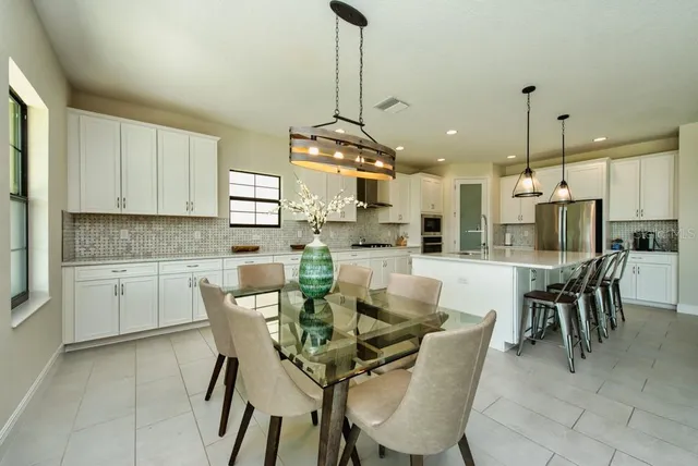 a kitchen with stainless steel appliances kitchen island granite countertop a table chairs and a refrigerator