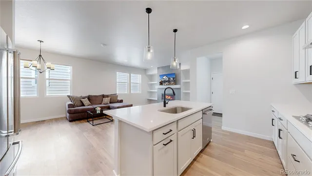 a kitchen with stainless steel appliances granite countertop a sink and a wooden floor