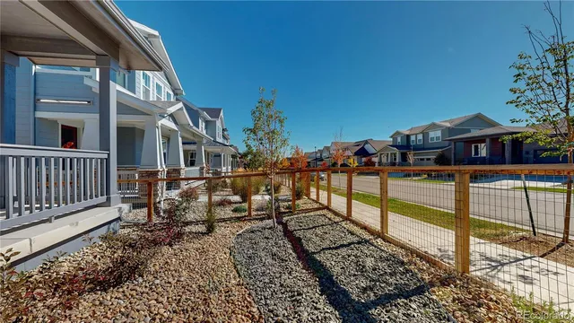 a view of a brick house with large windows and a wooden fence