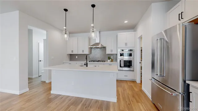 a large kitchen with stainless steel appliances a refrigerator a sink and a stove