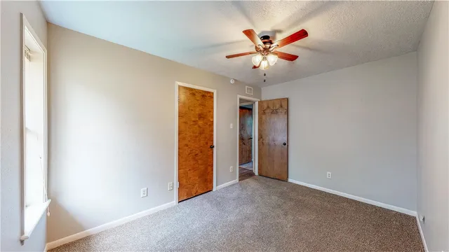 an empty room with closet and a ceiling fan