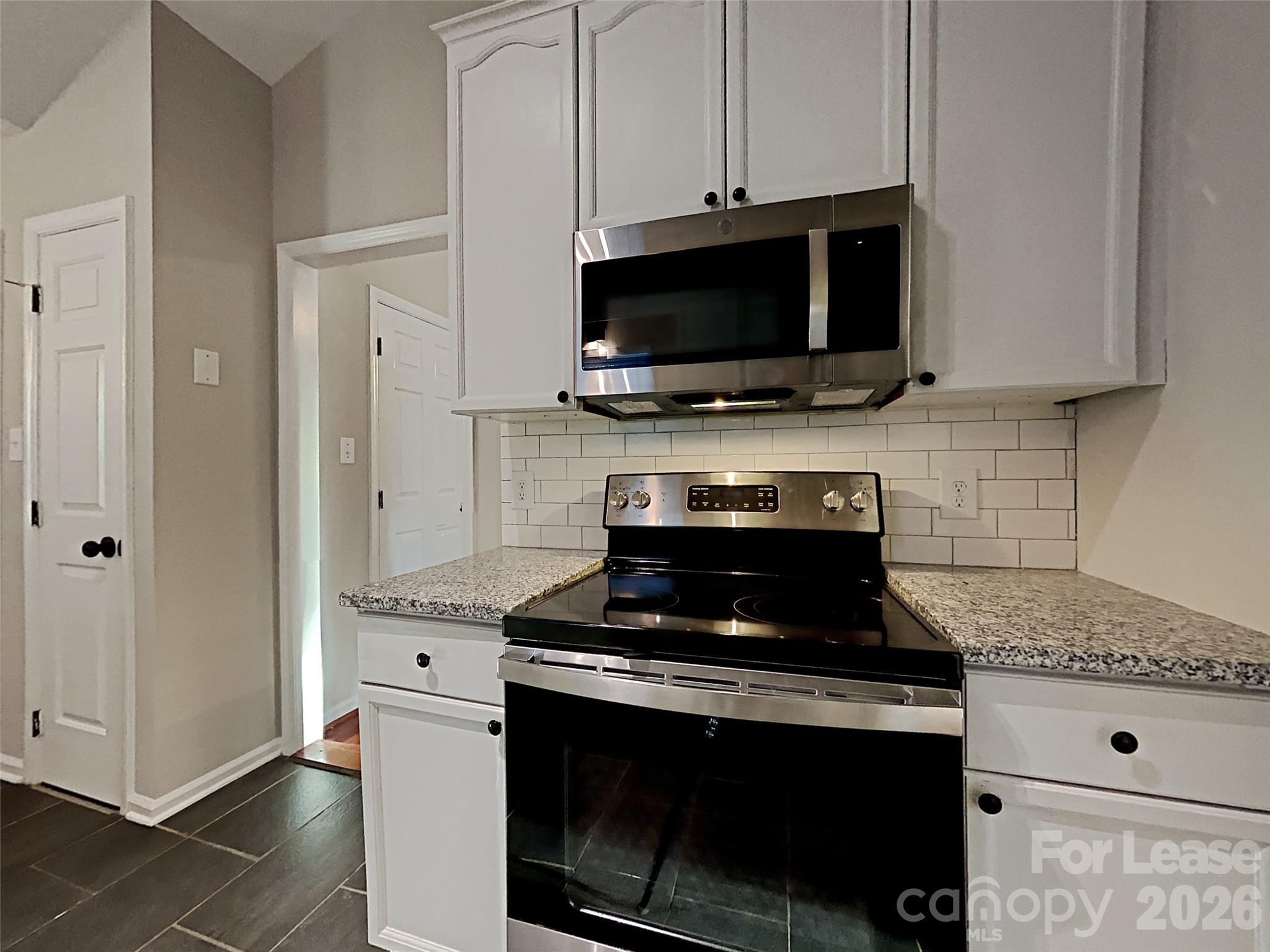 10715 Spruce Mountain Road Charlotte, NC 28214 - Photo 4 of 26 a kitchen with stainless steel appliances a stove a microwave and cabinets