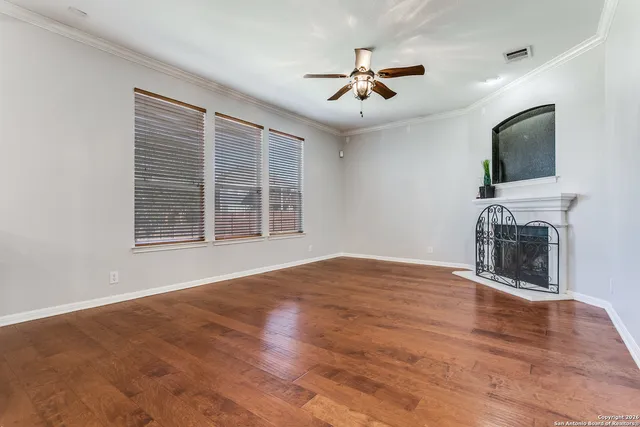 a view of empty room with wooden floor and fan