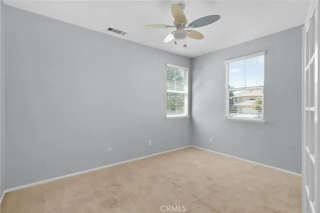 an empty room with windows and fan