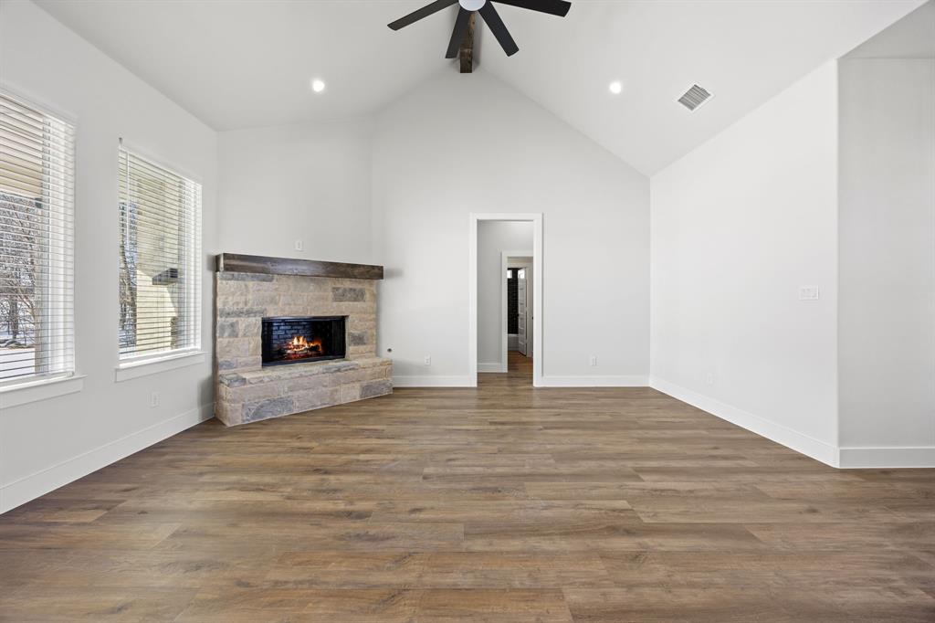 73 Dove Landing Rd Valley View Valley View, TX 76272 - Photo 13 of 30 Unfurnished living room with a stone fireplace, dark wood-style flooring, a high ceiling, a ceiling fan, and recessed lighting