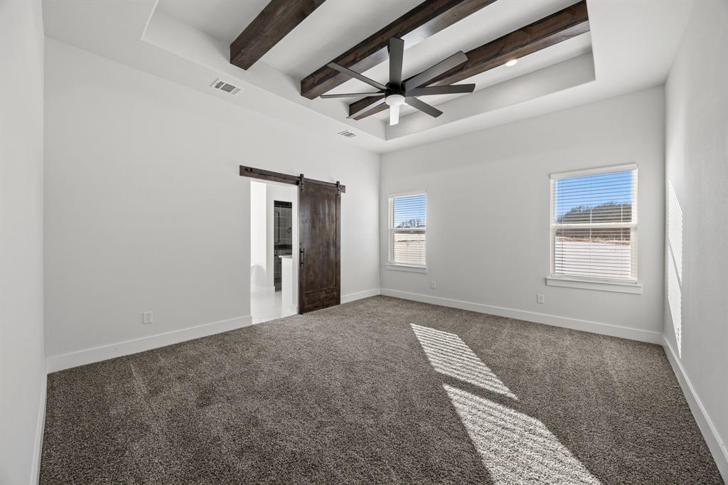 73 Dove Landing Rd Valley View Valley View, TX 76272 - Photo 14 of 30 Unfurnished bedroom with a barn door, beamed ceiling, carpet, ceiling fan, and a tray ceiling