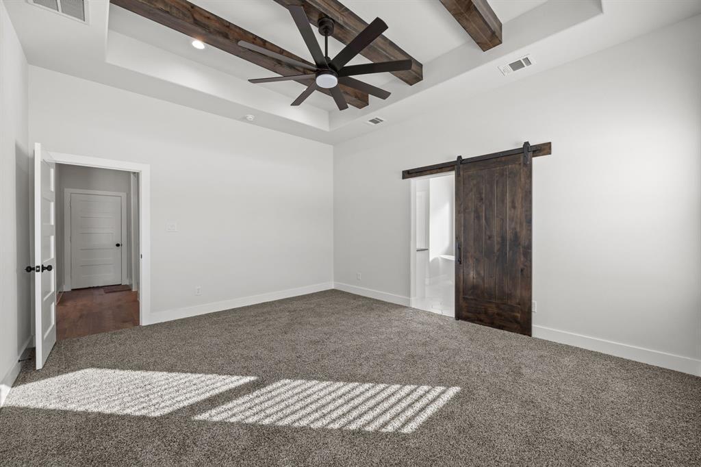 73 Dove Landing Rd Valley View Valley View, TX 76272 - Photo 15 of 30 Unfurnished bedroom with a barn door, a tray ceiling, carpet flooring, a ceiling fan, and beam ceiling