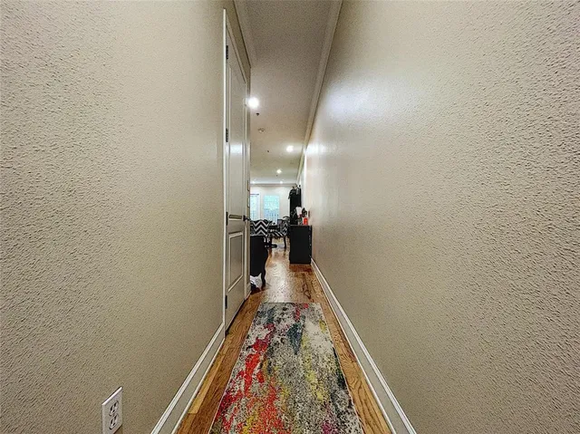 a view of a hallway with wooden floor and a bathroom