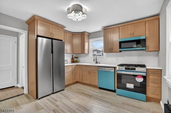 a kitchen with stainless steel appliances granite countertop a refrigerator a stove top oven a sink and dishwasher with wooden floor
