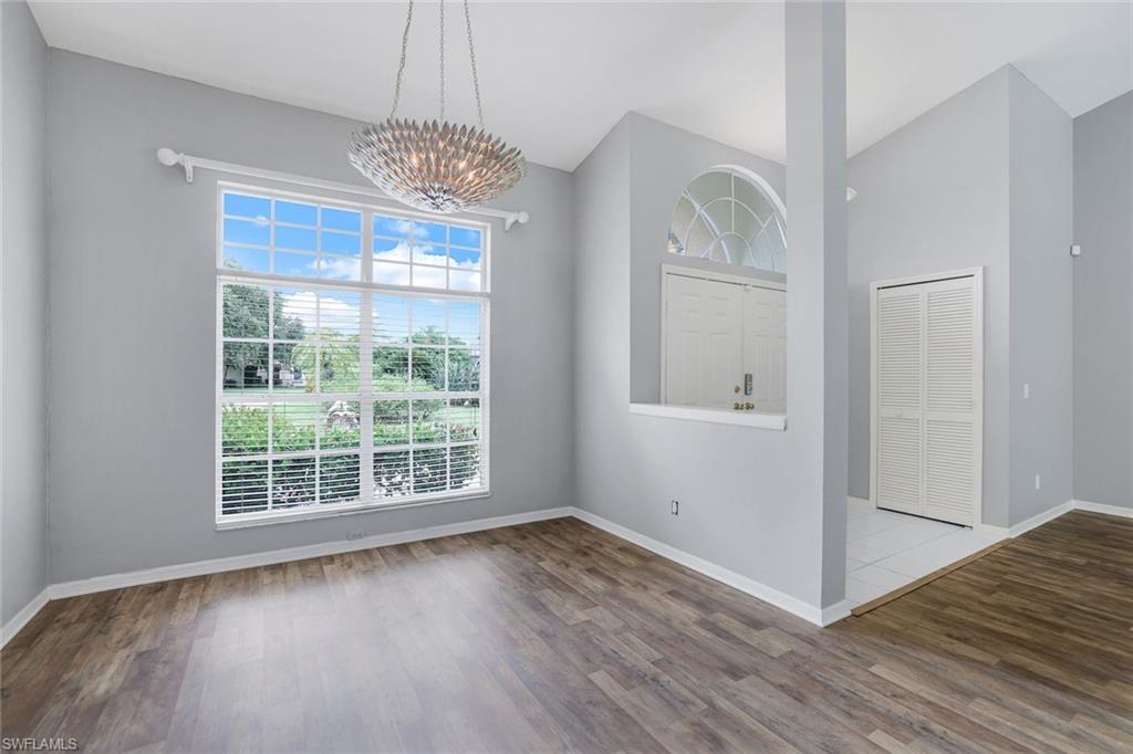 7786 Scarlet Court Naples, FL 34104 - Photo 6 of 19 an empty room with wooden floor chandelier and windows