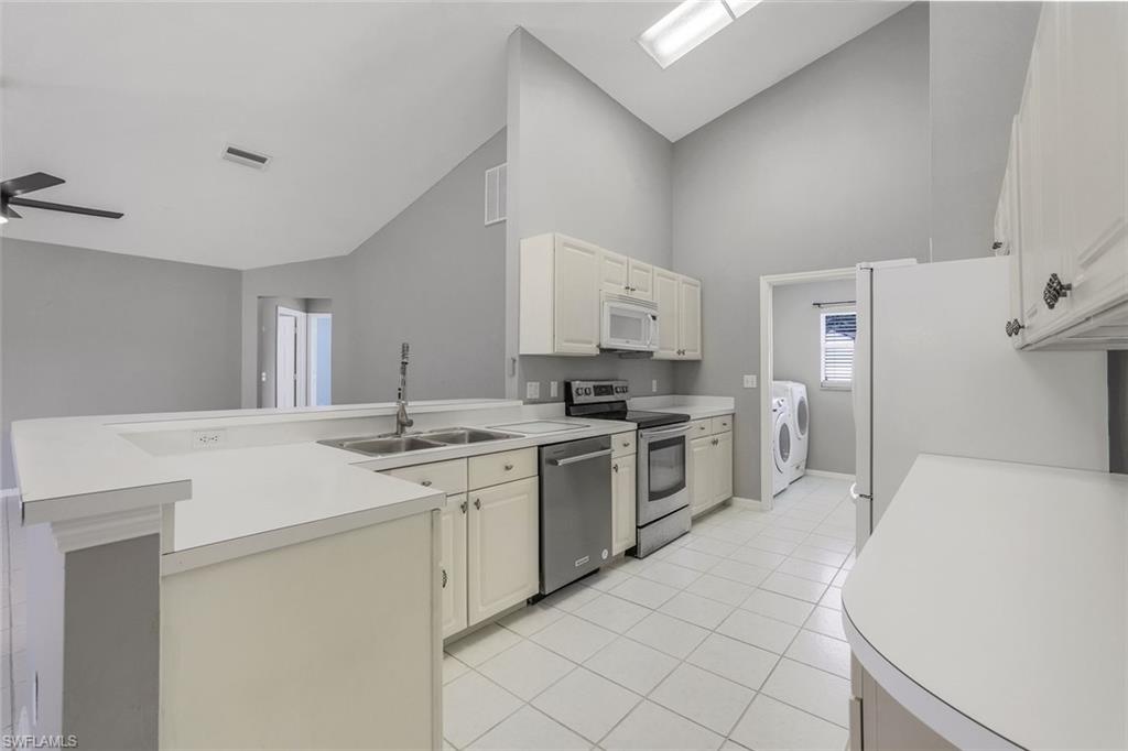 7786 Scarlet Court Naples, FL 34104 - Photo 7 of 19 a kitchen with white cabinets and white appliances